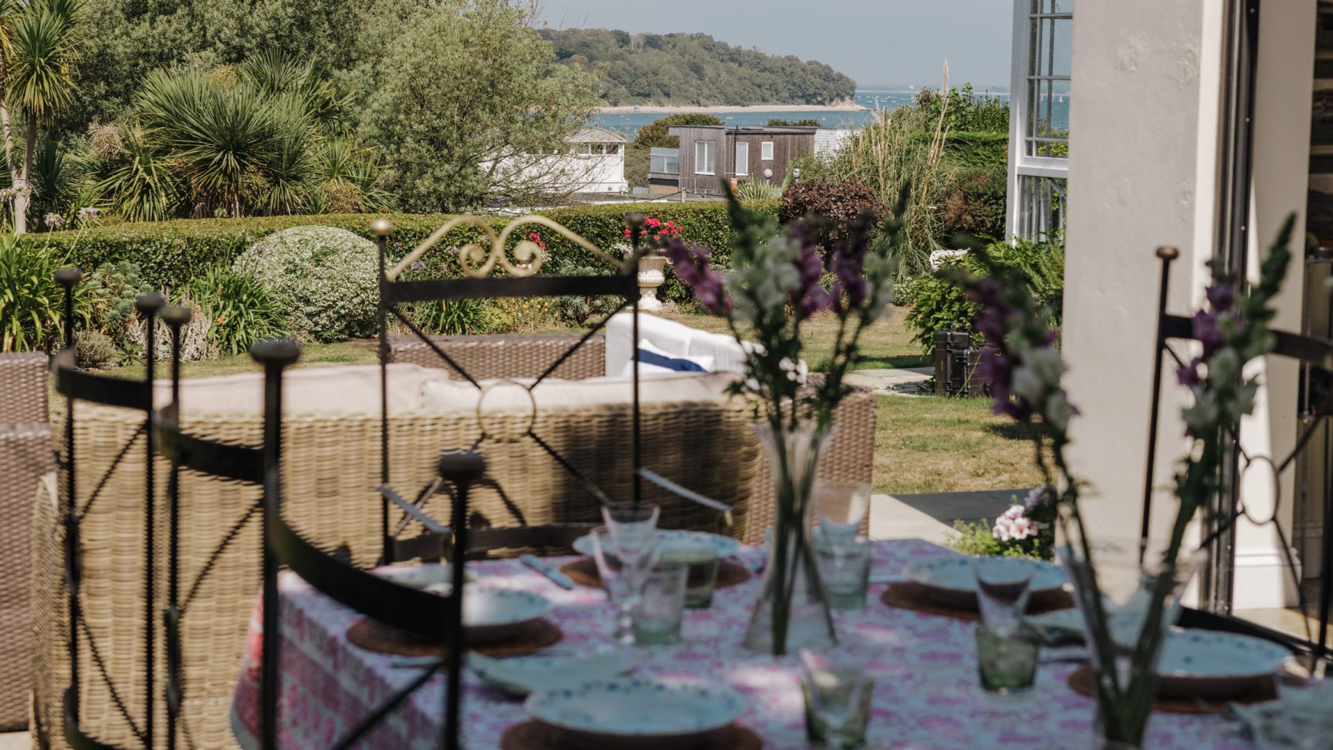 table set with plates on the patio with the sea in the distance