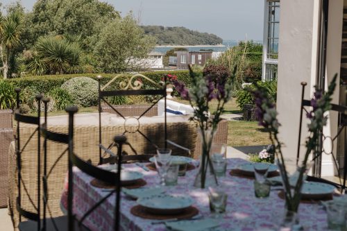 table set with plates on the patio with the sea in the distance